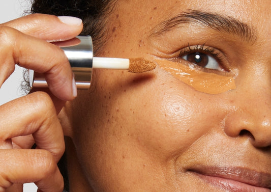 Model applies Milk Makeup Future Fluid All Over Cream Concealer to her under eye area.