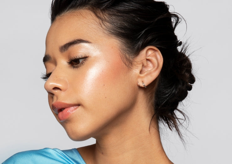 Portrait of a model wearing Milk Makeup highlighter on their cheekbone on a white background